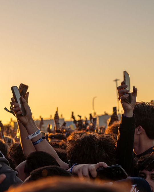 Golden-hour festival crowd with phones raised