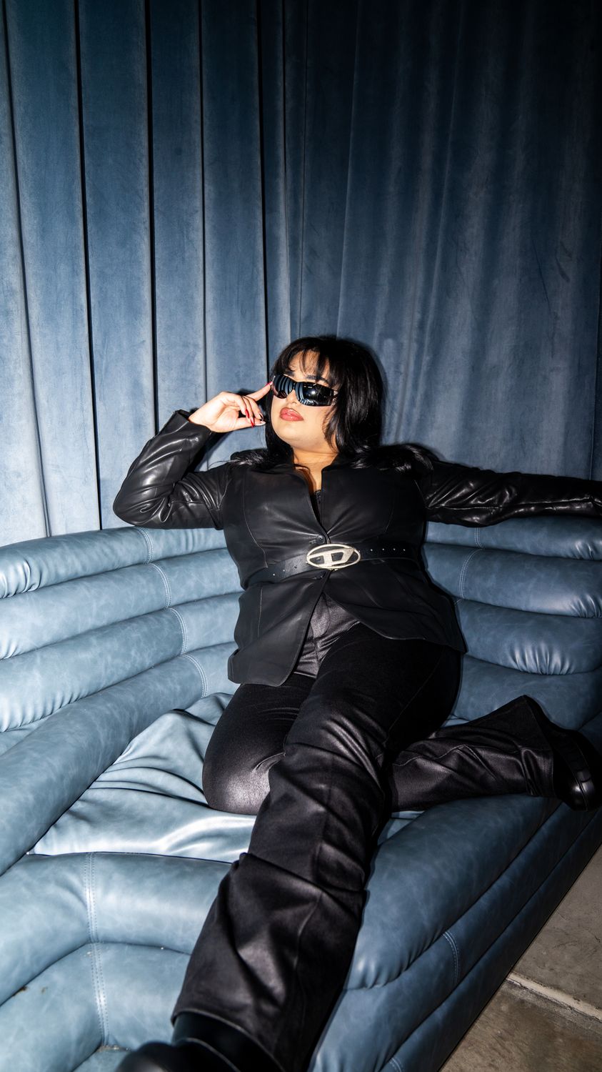 Model in black leather and sunglasses lounging on a blue leather sofa