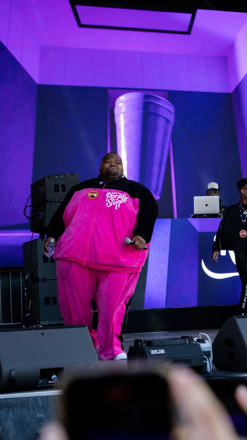 Performer in a pink suit on a purple-lit stage