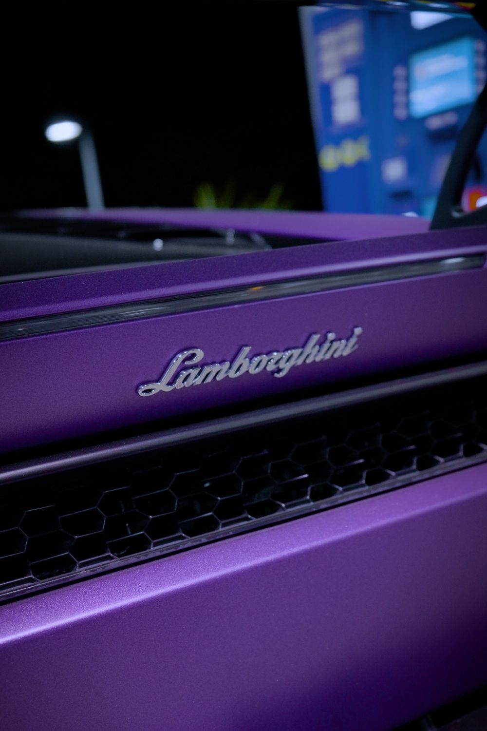 Close-up of the Lamborghini script and engine-cover vent on a purple supercar